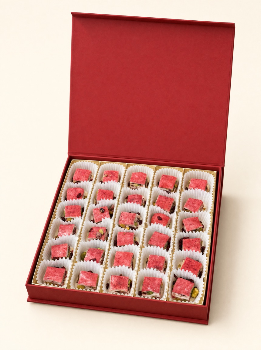 Open red Pure Red Gold gift box of barberry-dusted squares in white paper cups on warm ivory